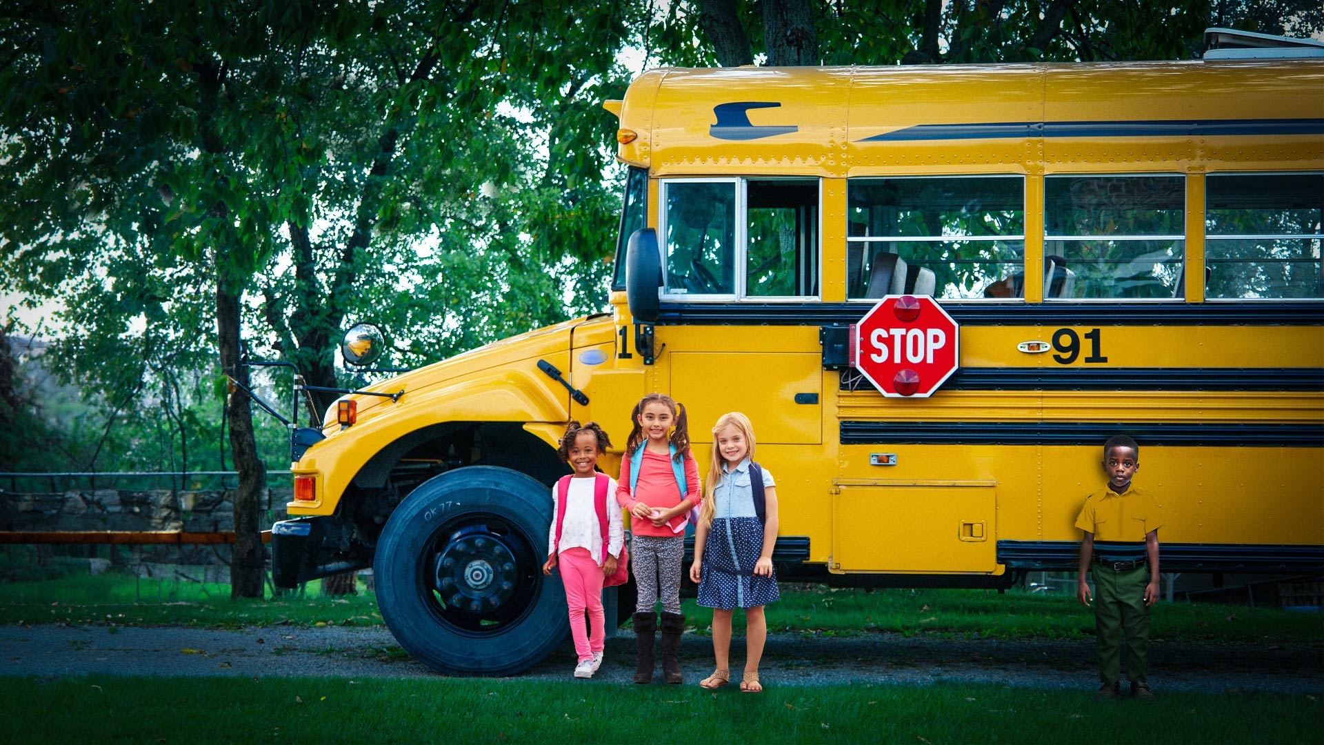 Photo of children standing beside a school bus